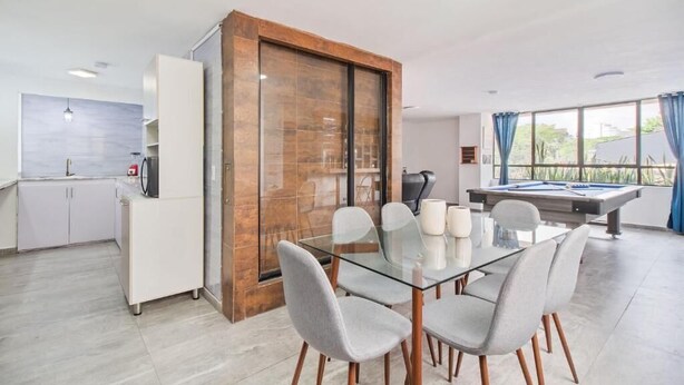 A modern kitchen with white cabinets, a glass dining table, and a pool table. - 2bedroom with pooltable 1 block -Lleras  (Medellín)
