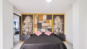 A modern bedroom with a large bed, a decorative headboard, and a mirror. - 2bedroom with pooltable 1 block -Lleras  (Medellín)