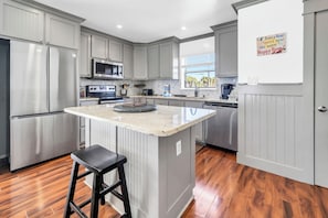 A kitchen with grey cabinets, stainless steel appliances, a marble island, and a wooden floor. - Sunchase 10A* Gulf Front Townhome with Private Beach Access & Gulf Views (Miramar Beach)