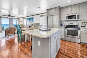 A kitchen with a central island, stainless steel appliances, and a view to the outside. - Sunchase 10A* Gulf Front Townhome with Private Beach Access & Gulf Views (Miramar Beach)