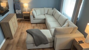 A modern living room with a sectional sofa, a wooden coffee table, a TV, and a small side table with a lamp. - Entire home just 10 minutes from Pittsburgh's North Shore (Glenshaw)