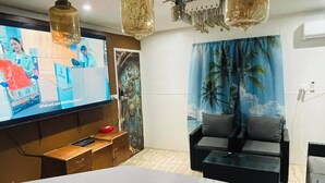 Un salon moderne doté d’un téléviseur à écran plat, d’un canapé, d’une table basse et d’une fresque murale décorative.