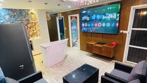 Un salon moderne doté d’un téléviseur à écran plat, de sièges confortables et d’un luminaire décoratif au plafond.