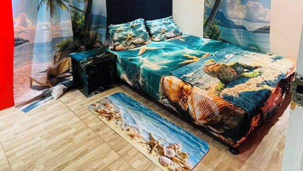 Un dormitorio con cama, cortinas, una mesita de noche y una pequeña mesa.