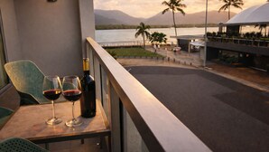 A balcony with two chairs, a table, and two wine glasses with a bottle of wine. - Cairns Harbour Haven | Marina Views | Pool & Spa | near Reef Terminal (Cairns City)