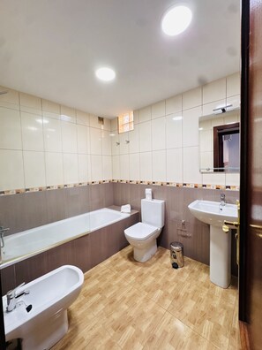 A bathroom with a bathtub, toilet, bidet, and sink. - Holiday Apartment Gara (Adeje)