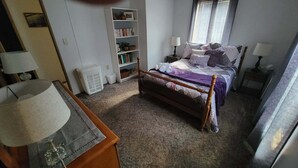 A bedroom with a bed, bedside tables, a bookshelf, and a window with blinds. - Cozy 2 bedroom Lake Cottage on Lamoka Lake in Bradford New York (Bradford)