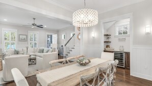 A spacious living room with a large wooden dining table, white sofas, and a chandelier. - 🎨 WaterColor ~ Golf Cart | Bikes | Private Beach | 4 Heated Pools & Lazy River (Watercolor)