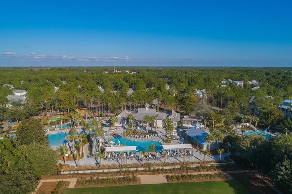An aerial view of a resort with multiple swimming pools, a golf course, and dense surrounding greenery. - WaterColor 2Bedroom– Pools, Beach & Bikes (Santa Rosa Beach)