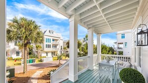 A covered porch with a view of a residential area, including a hotel and other buildings. - Large Family Getaway – Pool, Golf Cart, Sleeps 17 (Santa Rosa Beach)