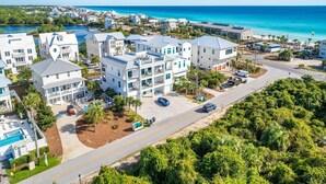 A coastal residential area with white buildings, a clear blue sky, and a view of the ocean. - Large Family Getaway – Pool, Golf Cart, Sleeps 17 (Santa Rosa Beach)
