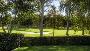 A well-maintained golf course with a sand bunker, surrounded by dense trees and a neatly trimmed hedge. - Golfside Escape – Stylish 3BR Townhouse in Robina (Robina)