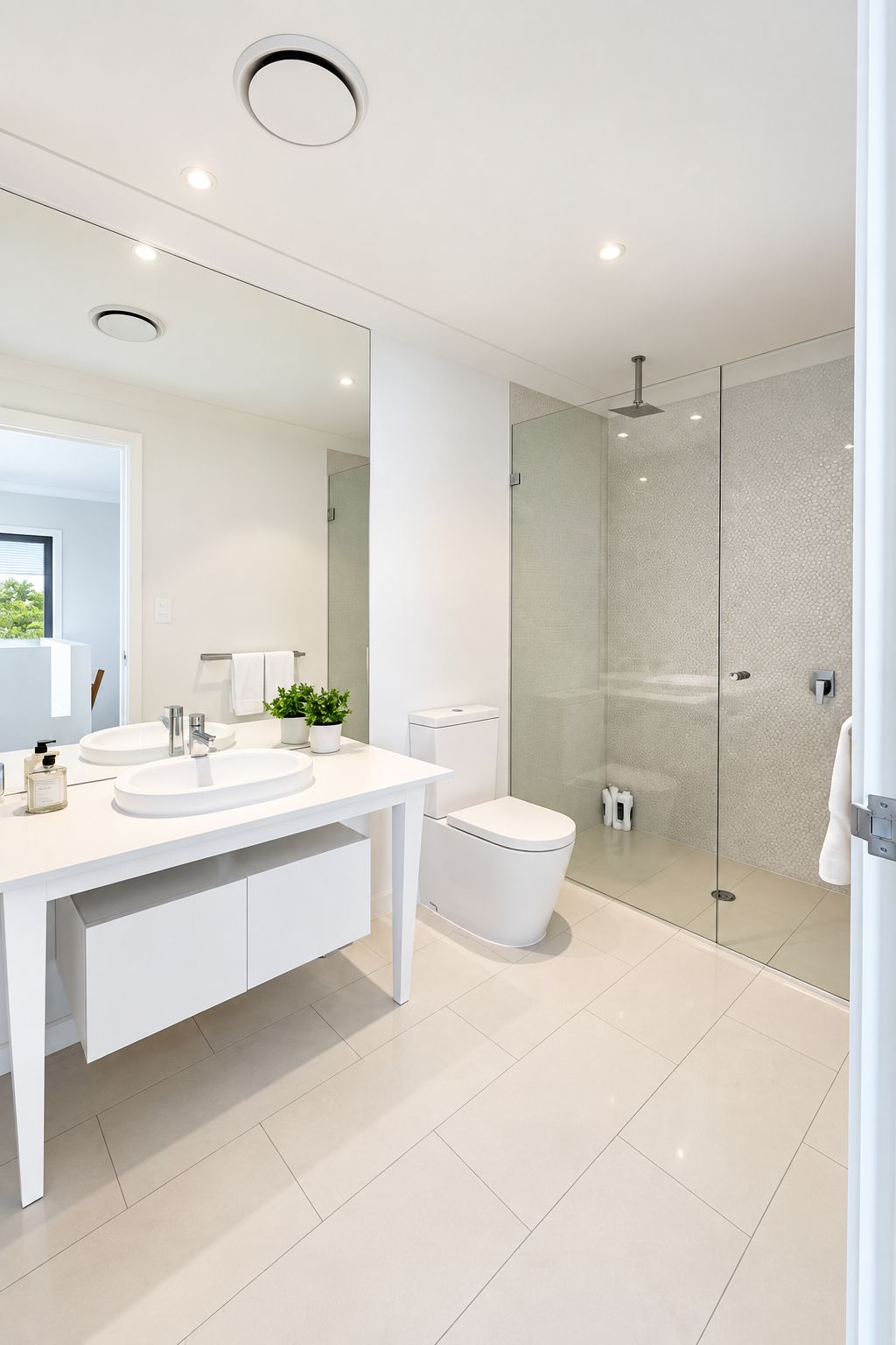 A modern bathroom with a white vanity, two sinks, a toilet, and a glass-enclosed shower.