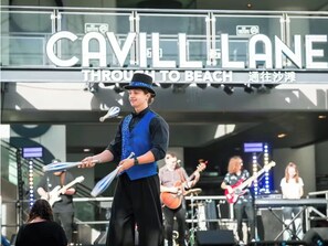 A band performing on stage with a sign reading "Cavill Lane Through to Beach".