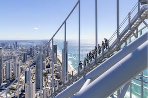 A high-rise building with a glass facade overlooking a coastal cityscape.