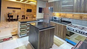 Una cocina moderna con una isla central, electrodomésticos integrados y un comedor al fondo.