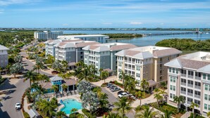 A resort with multiple buildings, a swimming pool, and a view of a bridge and water. - One Particular Penthouse | Top-Floor Condo at Margaritaville Near Anna Maria Island (Bradenton)