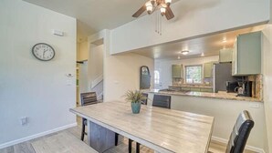 Un vaste espace dédié à la salle à manger, avec une longue table, des chaises et un ventilateur de plafond.