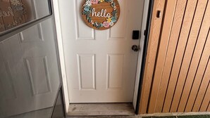 A white door with a 'hello' sign, a number '28' sign, and a 'hello' doormat. - Convenient & Cozy condo on 400 (Logan)