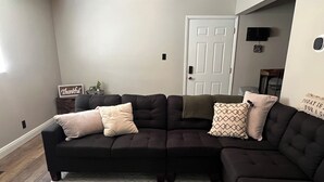 A sectional sofa with multiple cushions, a patterned rug, and a door in the background. - Convenient & Cozy condo on 400 (Logan)