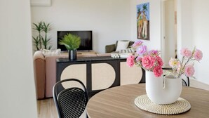 Una sala de estar moderna con un sofá, una mesa de centro con un florero, un televisor y un cuadro en la pared.