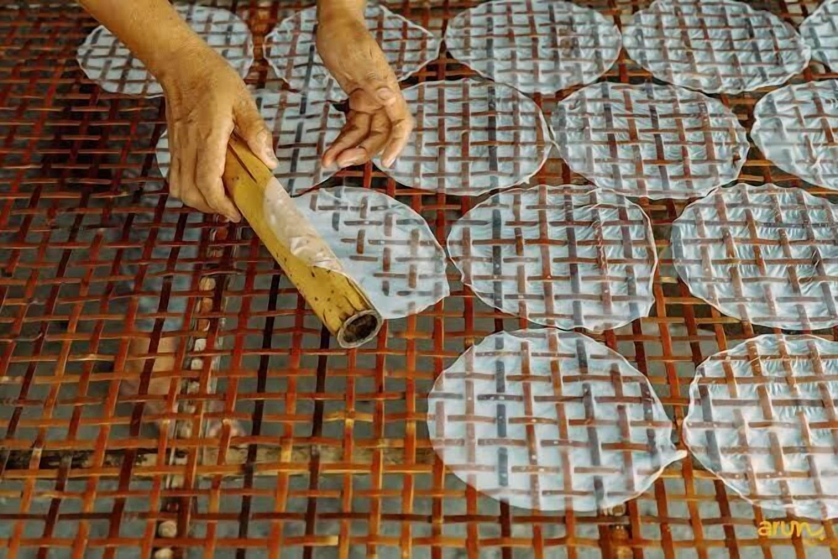 A hand placing a woven mat on a grid floor.