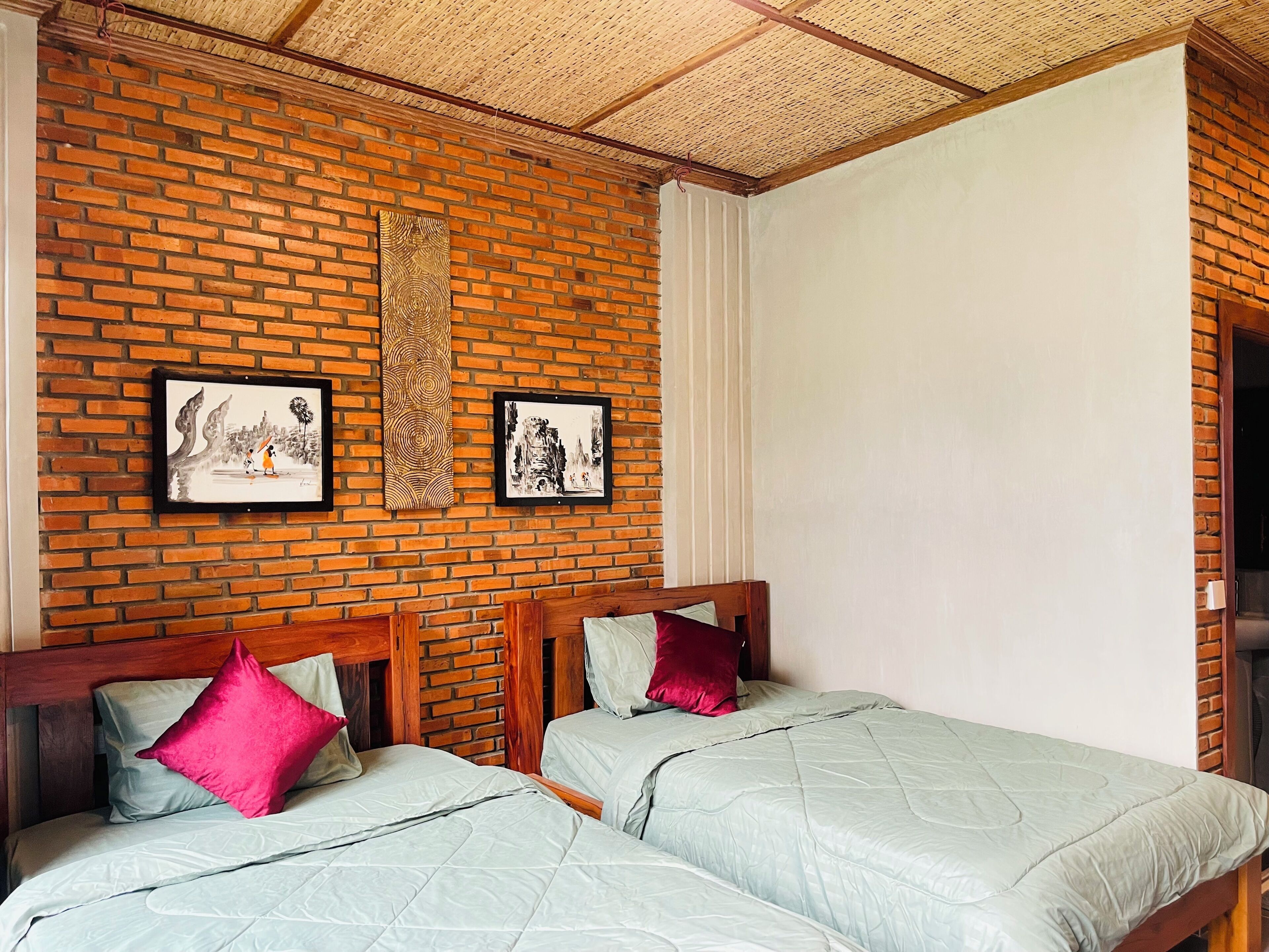 Una habitación con pared de ladrillo, dos camas con cabeceros de madera y una obra de arte en la pared.