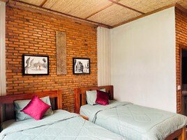Una habitación con pared de ladrillo, dos camas con cabeceros de madera y una obra de arte en la pared.