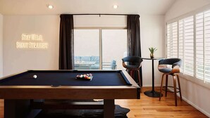 Une table de billard avec des billes, une queue de billard et un panneau accroché au mur.