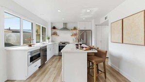 A modern kitchen with white cabinetry, a central island, and a bar stool. - Hideaway - In Old Town Scottsdale-Walk to Downtown (Scottsdale)