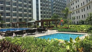 Un hotel con piscina, area relax all'aperto e vegetazione rigogliosa.