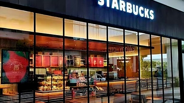Un negozio Starbucks con ampie vetrate, posti a sedere interni e una zona esterna ben visibile.