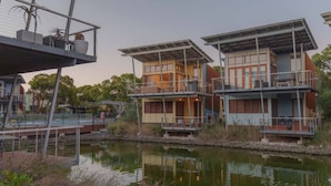 Un immeuble moderne à plusieurs étages, doté de balcons, situé au bord d’un plan d’eau.