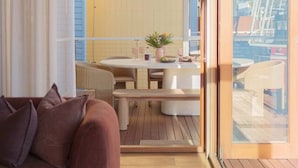 Un salon confortable avec un canapé, une table à manger et des chaises, et une vue sur l’extérieur par une grande fenêtre.