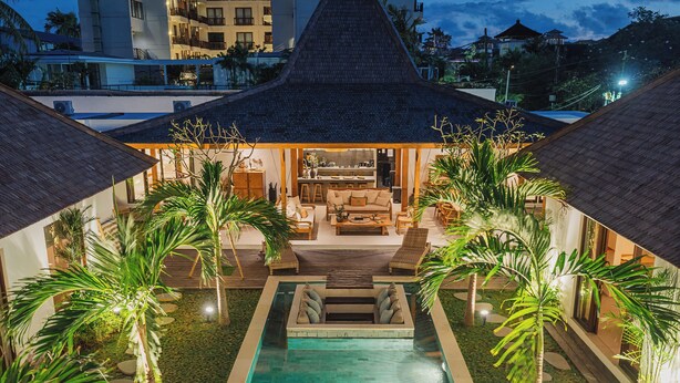 A pool area with a lounge chair and a sofa, surrounded by palm trees and a thatched-roof structure. - Villa Oomi by Alfred in Bali (Seminyak)