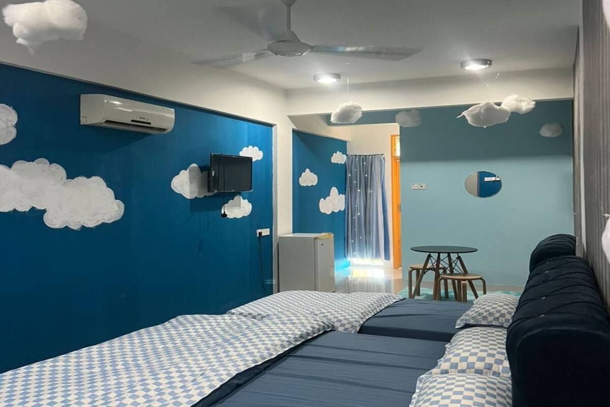 A room with two beds, a ceiling fan, a small table, and a TV.