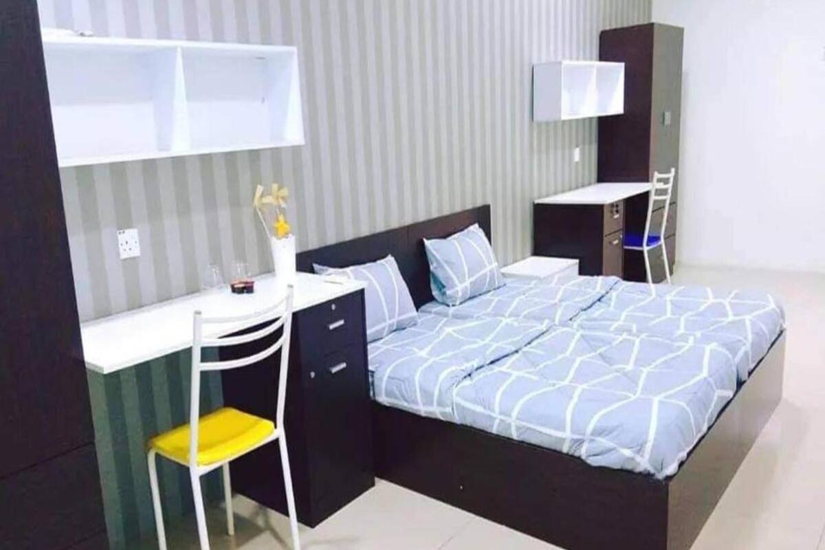 A compact bedroom with a bed, a desk, and a chair.