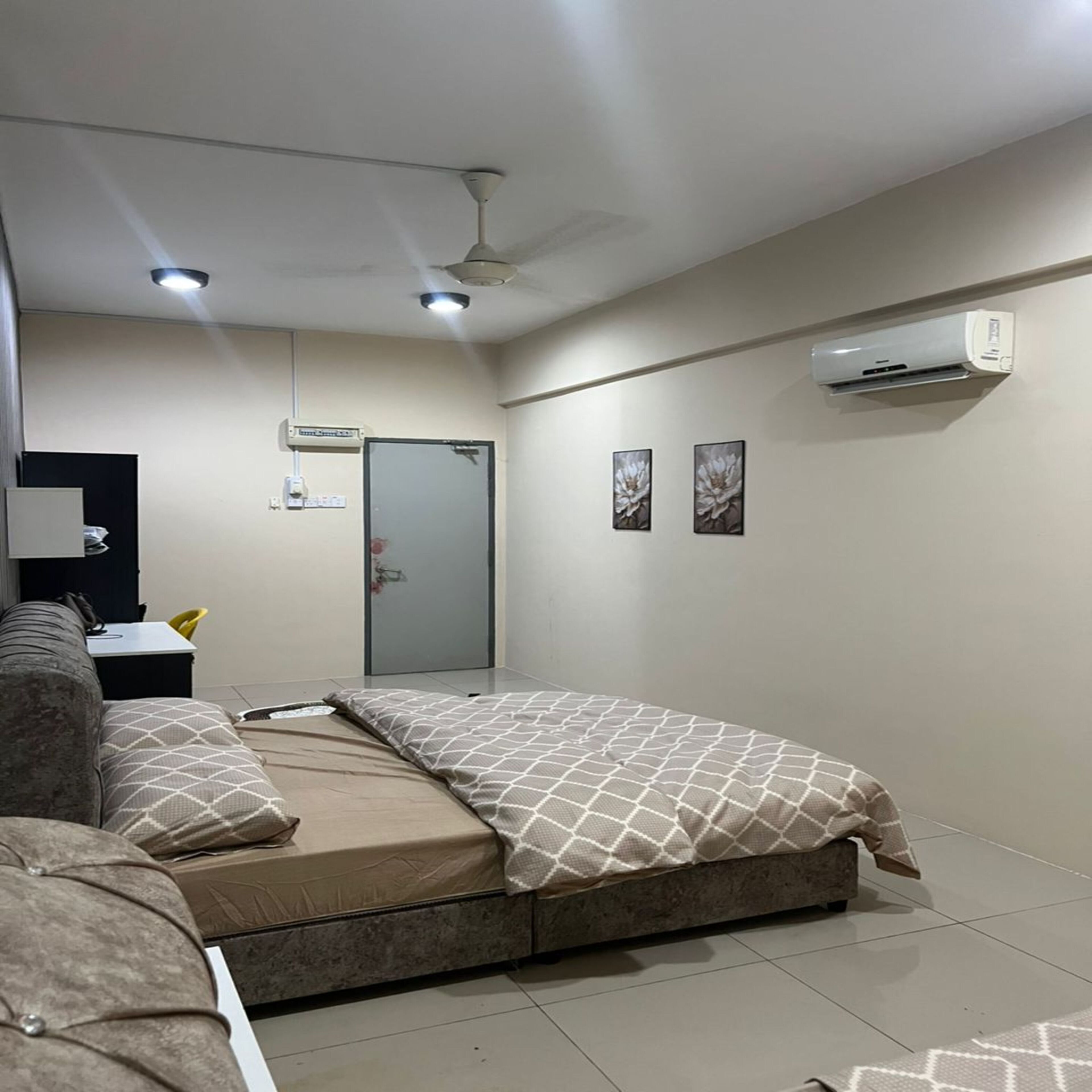 Un dormitorio con cama, sofá, escritorio y aire acondicionado.
