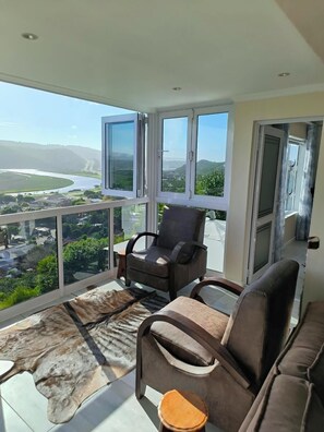 Un balcon avec un fauteuil en cuir, un canapé et un tapis en fourrure.