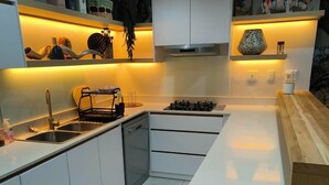 A modern kitchen with white cabinets, a central island, and under-cabinet lighting.