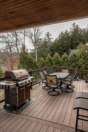 A wooden deck with a grill and outdoor furniture. - 4BR Dog Friendly Lakefront | Private Dock, Fireplace, Sleeps 8, Near Gunstock (Gilmanton)