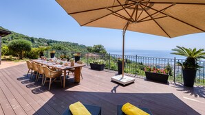 A wooden deck with a table and chairs, a large umbrella, and potted plants. - Villa Belvedere Condor  - S, Alassio, Italy (Alassio)