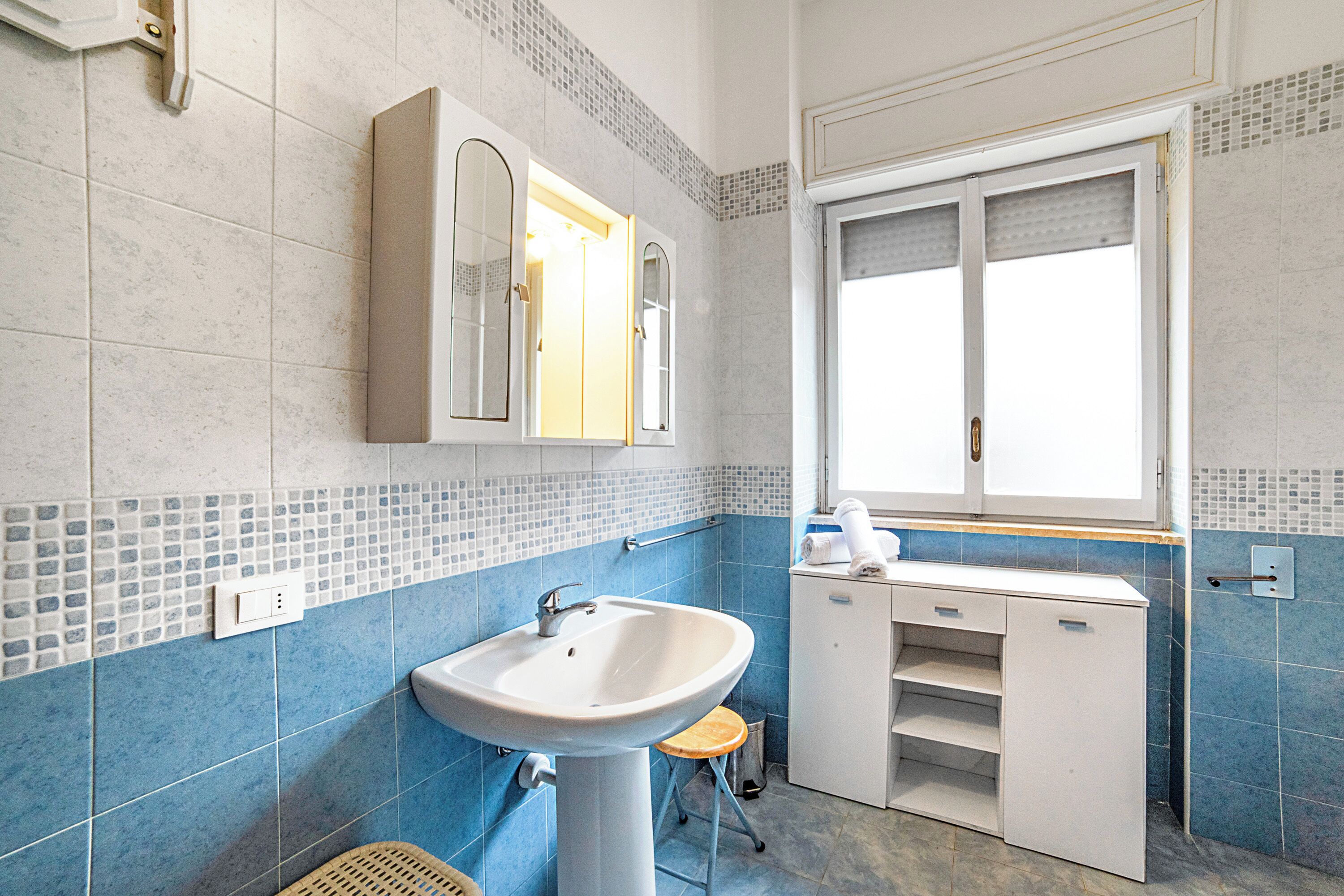 A bathroom with a sink, mirror, and window.