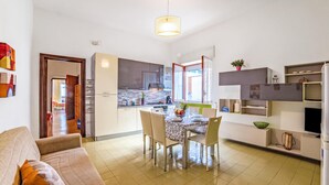 A modern kitchen with a dining area, a sofa, and a TV. - Sunny Sea-View Terrace in Torre dell’Orso, Melendugno, Italy (Melendugno)