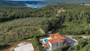 Una villa con piscina, rodeada de exuberante vegetación y vistas a un lago.