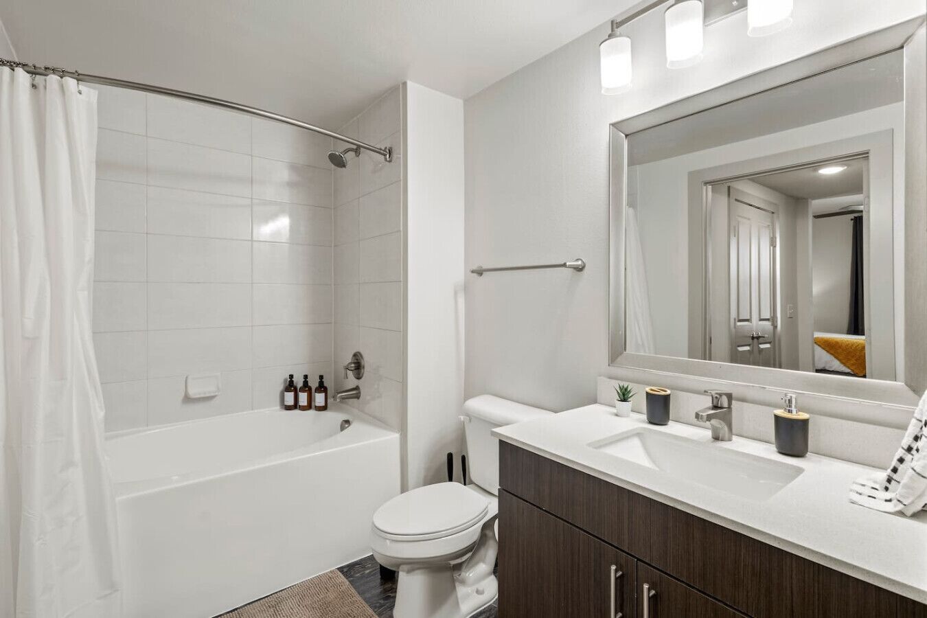 A modern bathroom with a bathtub, toilet, and vanity with a mirror.