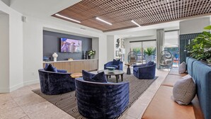 A modern lounge area with seating, a flat-screen TV, and a ceiling with wooden slats.