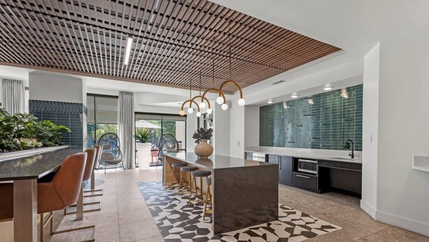 Una cocina moderna con una isla central, asientos tipo barra y un tapete con estampado geométrico.