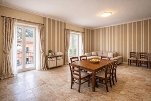 A dining area with a wooden table and chairs, a sofa, and striped walls. - Duplex Le Onde - Center & Parking, Ceriale, Italy (Ceriale)