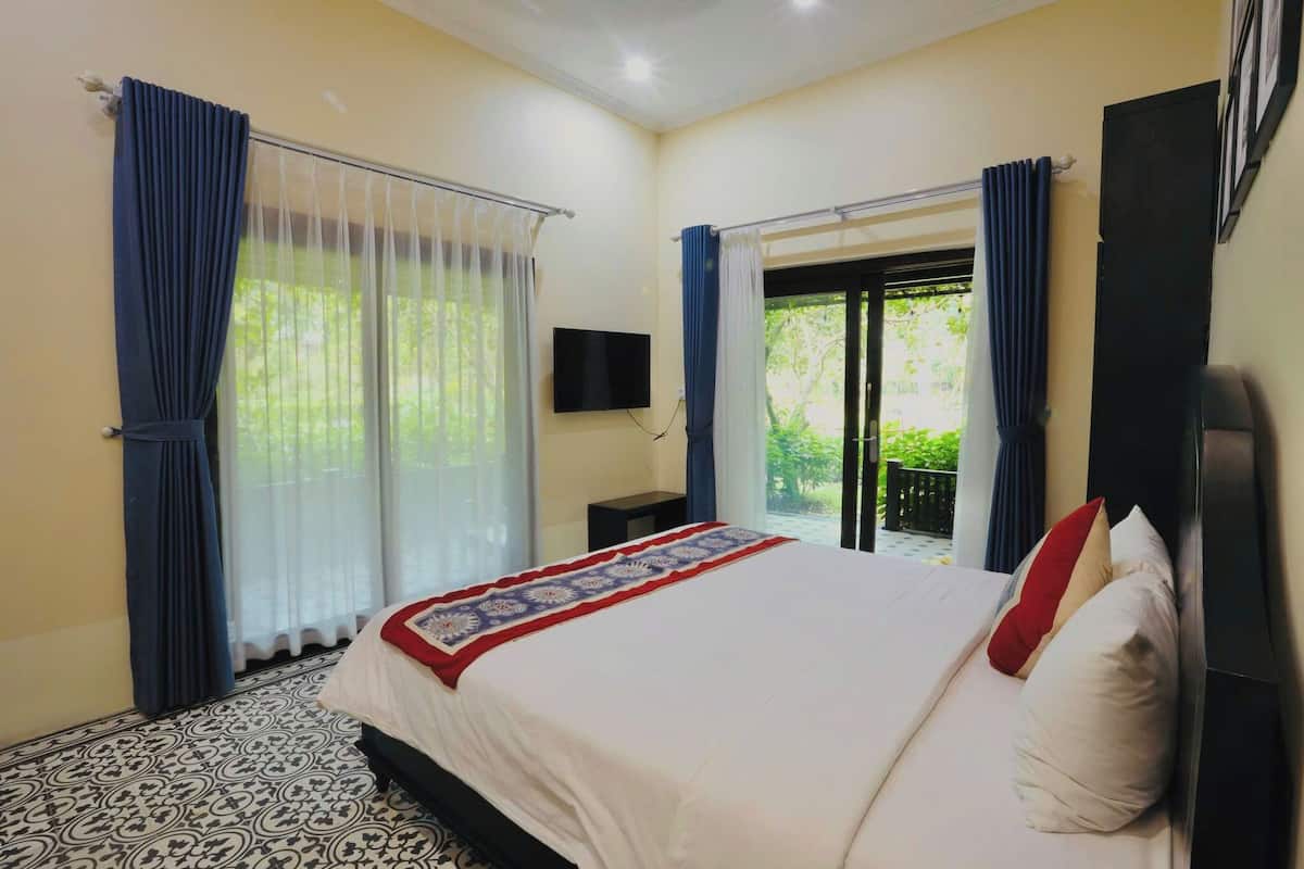 Habitación de hotel con una cama grande, un televisor de pantalla plana en la pared y un balcón con cortinas.